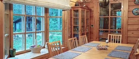 A wooden dining room with a large table, chairs, and a chandelier.