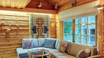 A cozy cabin interior with a sectional sofa, a small round table, and a large window.