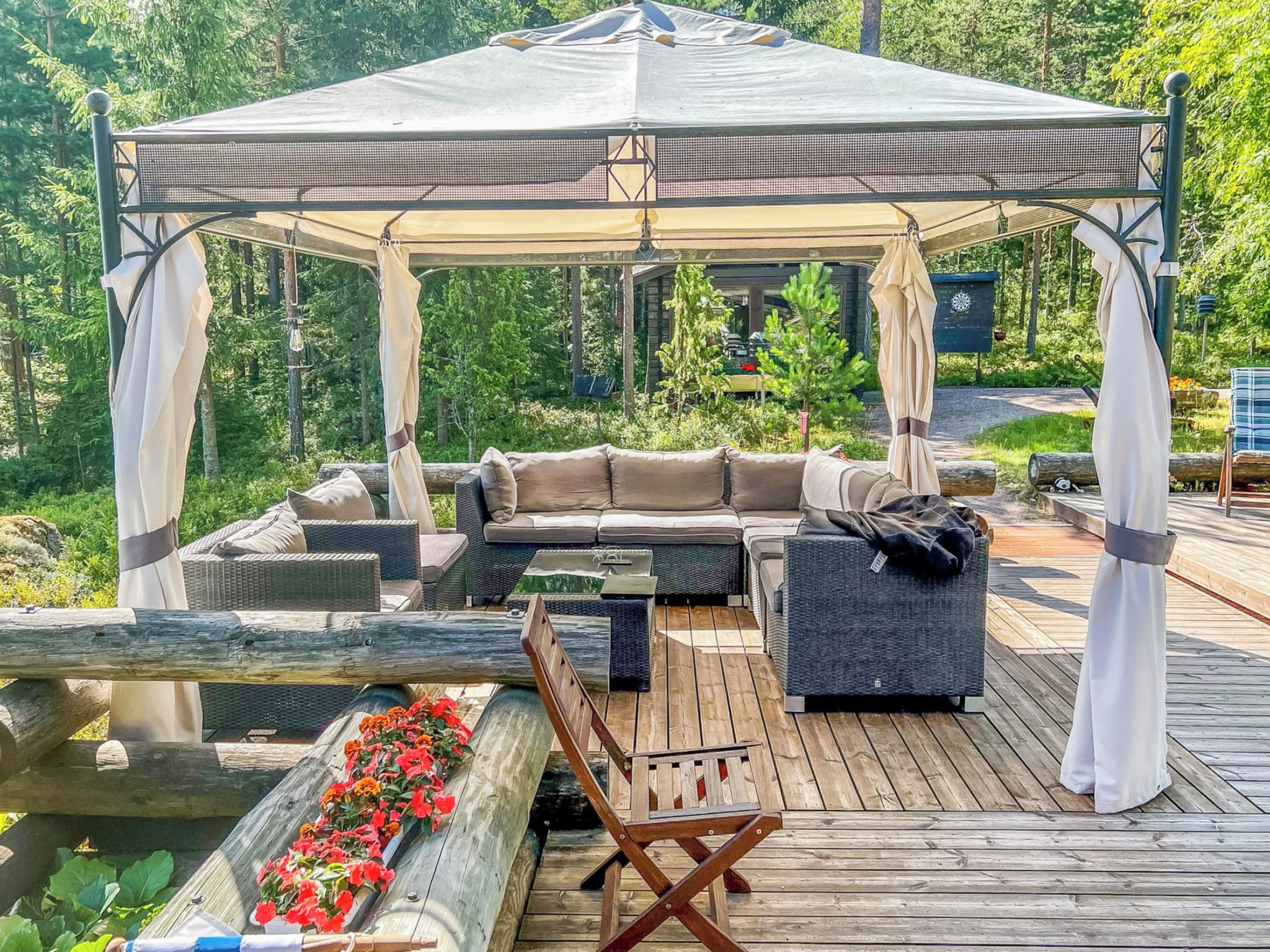 A covered outdoor seating area with a sofa, a wooden table, and a bench.