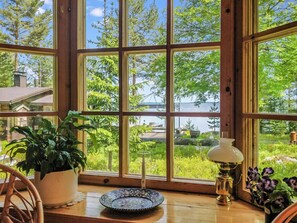 A room with large windows, a wooden table, a potted plant, a decorative lamp, and a view of a bridge and trees. - Lauluranta by Interhome (Padasjoki)