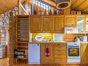 A wooden cabin kitchen with a refrigerator, stove, and wooden cabinets.