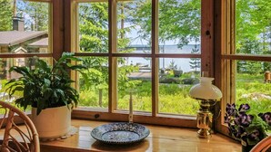 Quarto com amplas janelas que oferecem vista para um lago e vegetação ao redor.