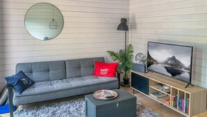 A modern living room with a grey sofa, a round mirror, a chandelier, a TV, and a bookshelf. - Kasnäs marina c 21 by Interhome (Kemiönsaari)