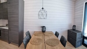 A modern dining area with a wooden table, woven placemats, and black chairs. A geometric pendant light hangs above, and a small black birdcage decorates the wall. - Kasnäs marina c 21 by Interhome (Kemiönsaari)