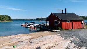 A red cabin by a lake with boats docked nearby. - Kasnäs marina c 21 by Interhome (Kemiönsaari)
