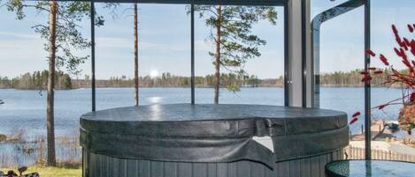 A hot tub with a view of a lake and trees.