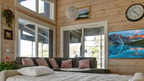 Et soveværelse med en stor seng, en sofa og et maleri af et bjerglandskab.