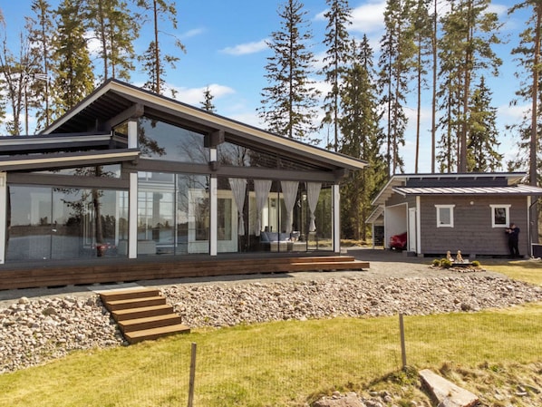 Een modern huis met twee verdiepingen, grote ramen en een overdekt terras.
