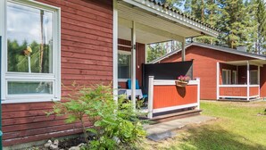 Een rode houten chalet met een veranda en een overdekt terras.