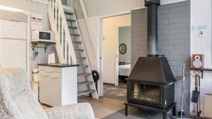 Een moderne woonkamer met een open haard, een trap en een keukenhoek.