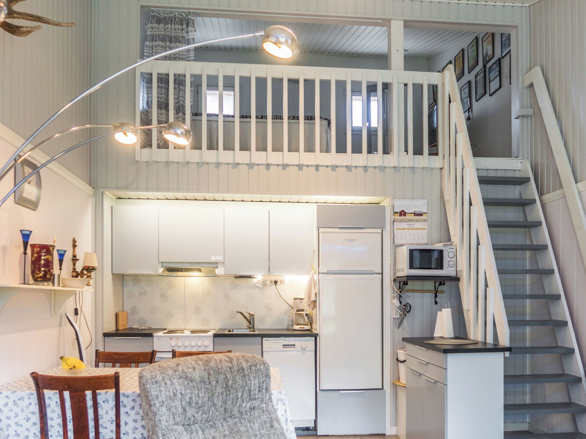 Eine kleine Küche mit Essbereich, einer Treppe und einem Schlafzimmer im oberen Bereich mit einem Balkon.