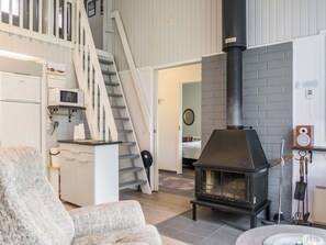 Een modern interieur met een trap, een keukenhoek en een houtkachel.
