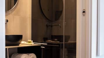 Un bagno moderno con doccia vetrata, uno specchio rotondo e un lavandino.