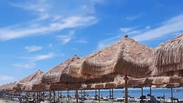 Perto da praia, areia branca, espreguiçadeiras, guarda-sóis