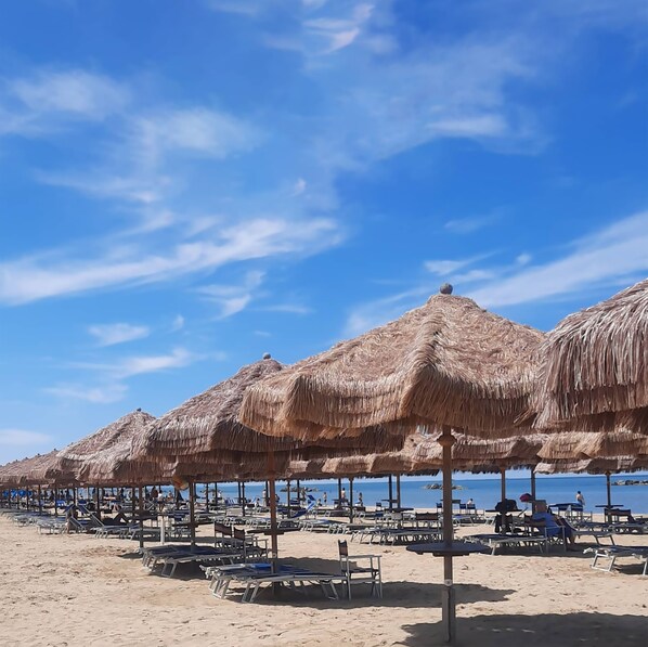 Vlak bij het strand, wit zand, ligstoelen aan het strand, parasols