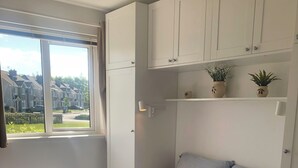 Ein Schlafzimmer mit Bett, Fenster, Heizkörper und Deckenleuchte.