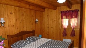 Une pièce en bois avec un lit, des rideaux et une fenêtre.