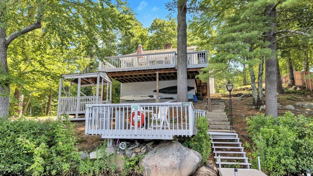 A house with a deck and a small bridge over a stream, surrounded by trees. - Baboosic Lake - Wonderful Classic S. NH Vacation Cottage all to Yourself (Merrimack)