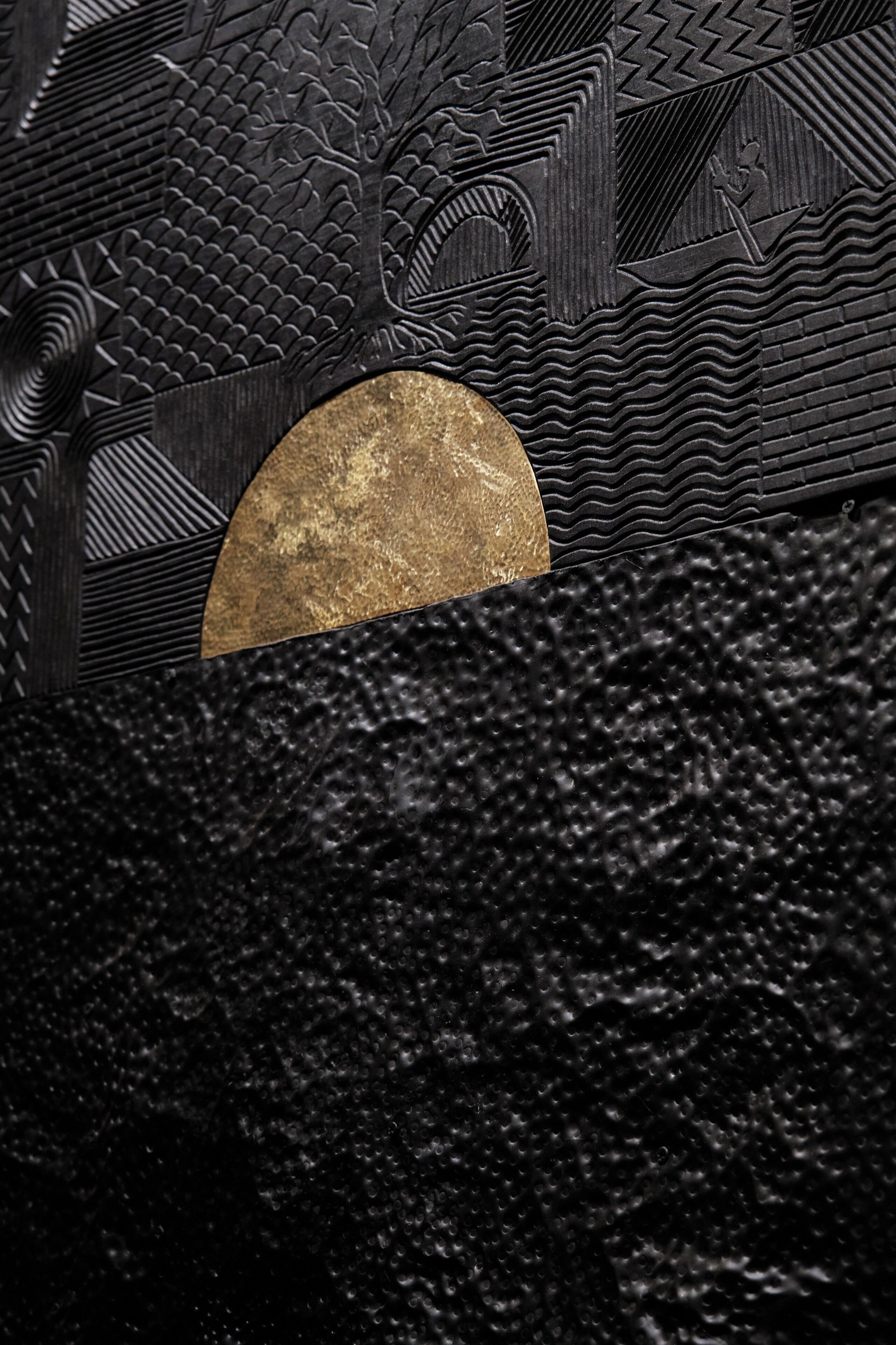 A textured wall with intricate patterns and a circular gold-colored object.