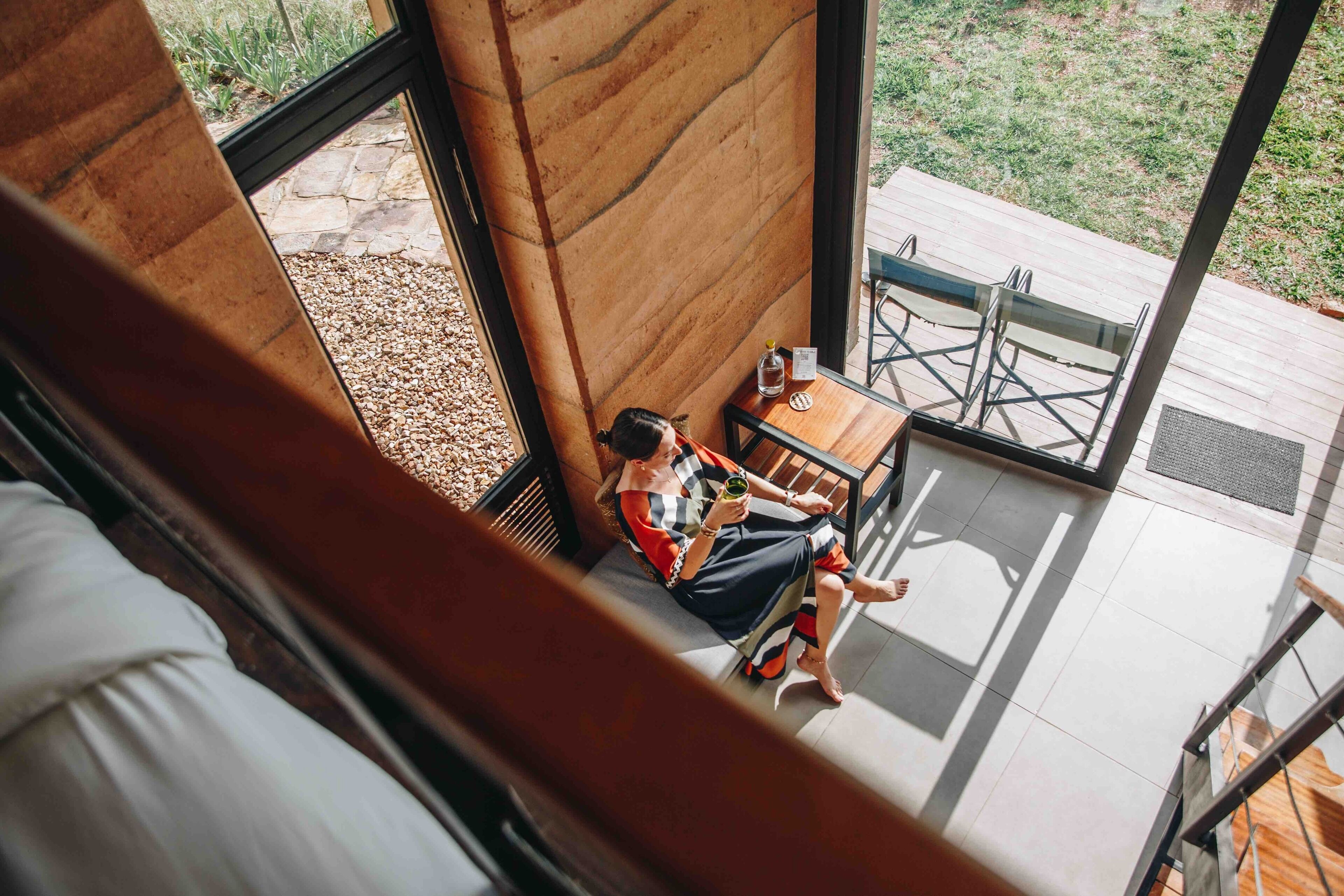 Una persona sentada a una mesa con vista a un jardín a través de una ventana.