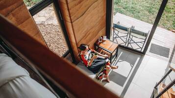 Una persona sentada a una mesa con vista a un jardín a través de una ventana.