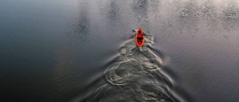 A kayak on a calm body of water with a wake behind it.