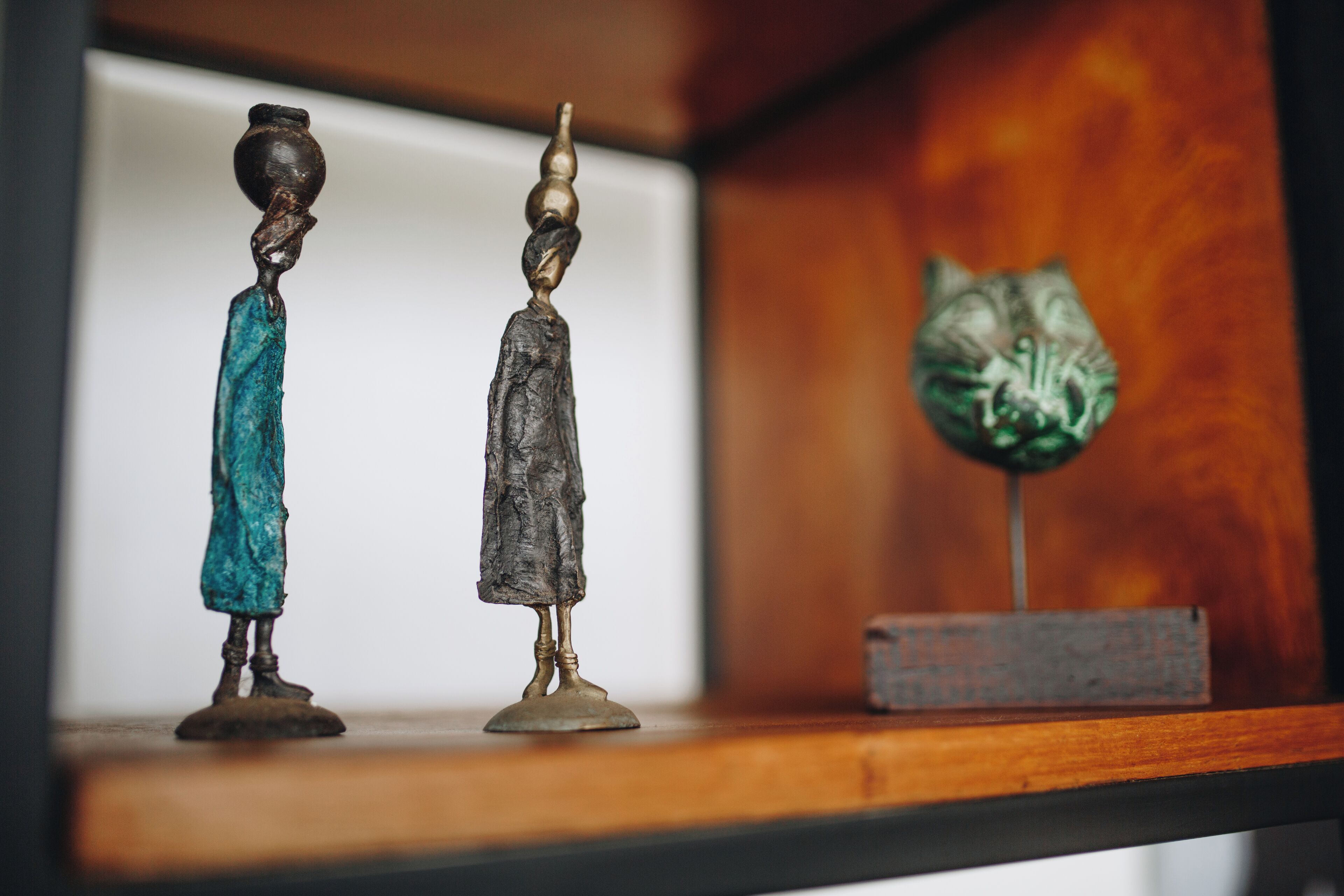 Two bronze sculptures on a wooden shelf.