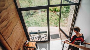 A modern interior with a large glass window, a wooden bench, and a staircase. - UMVA Muhazi (Muhazi)