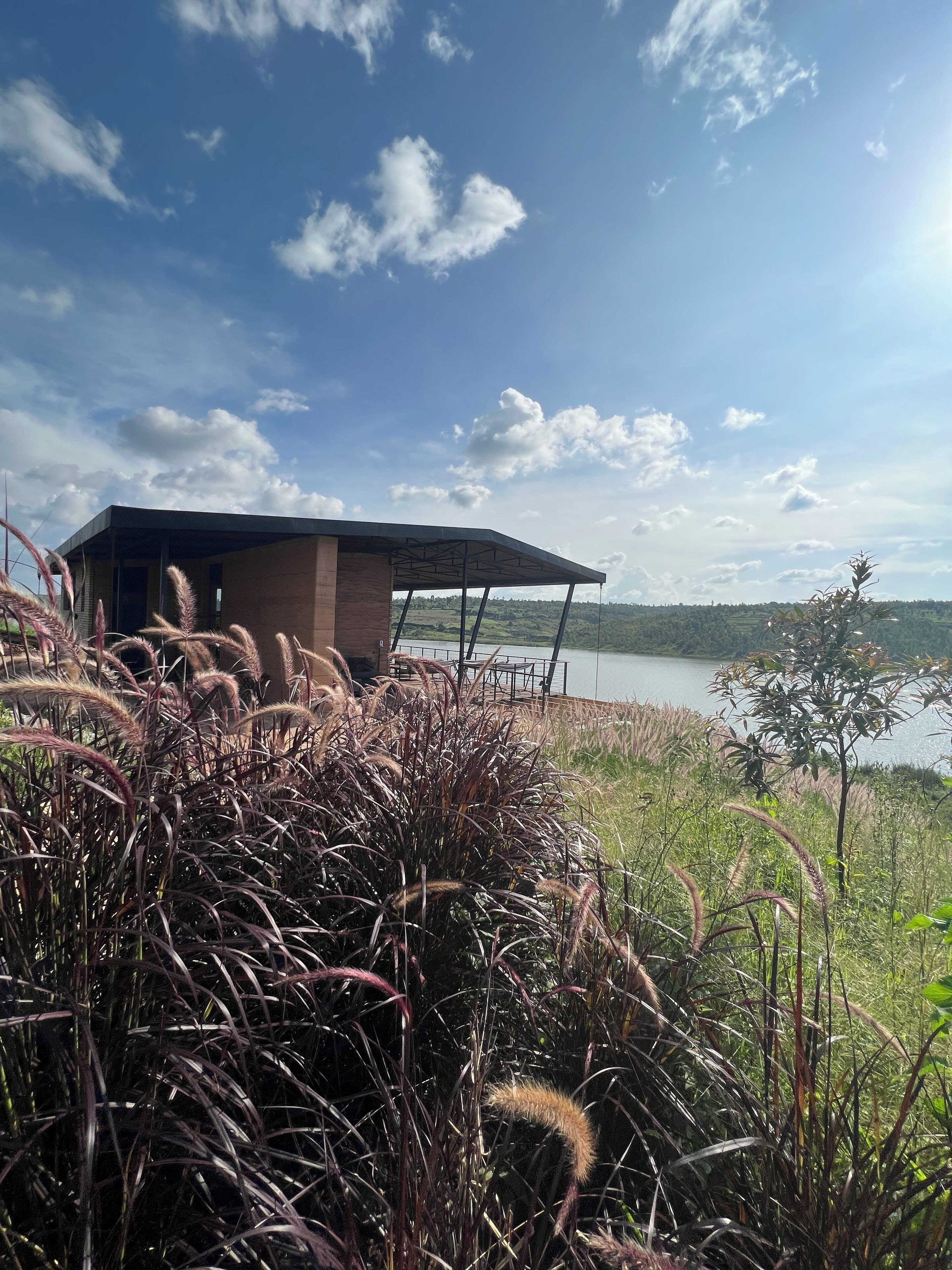 Un edificio moderno con un área exterior techada que da a un lago.