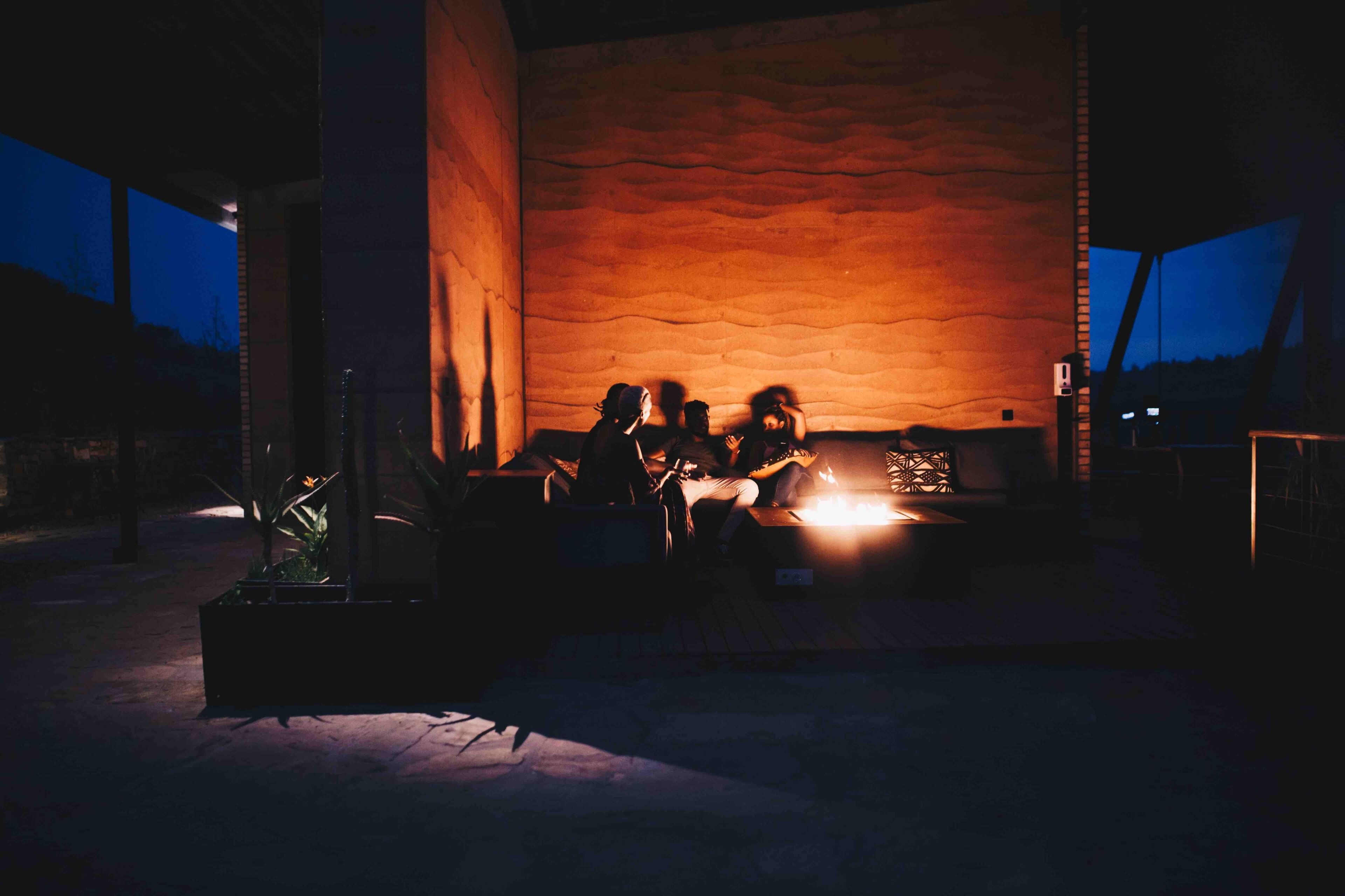 A group of people sitting around a fire in an outdoor setting at dusk.