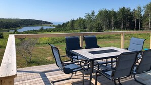 Une terrasse avec une table et des chaises donnant sur un lac et une forêt.