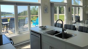 Une cuisine moderne dotée d’une grande fenêtre, d’un évier et d’un coin repas avec des chaises.