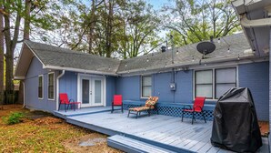 A blue house with a covered porch, two red chairs, and a covered object on the right. - Pine Bluff (Pine Bluff)
