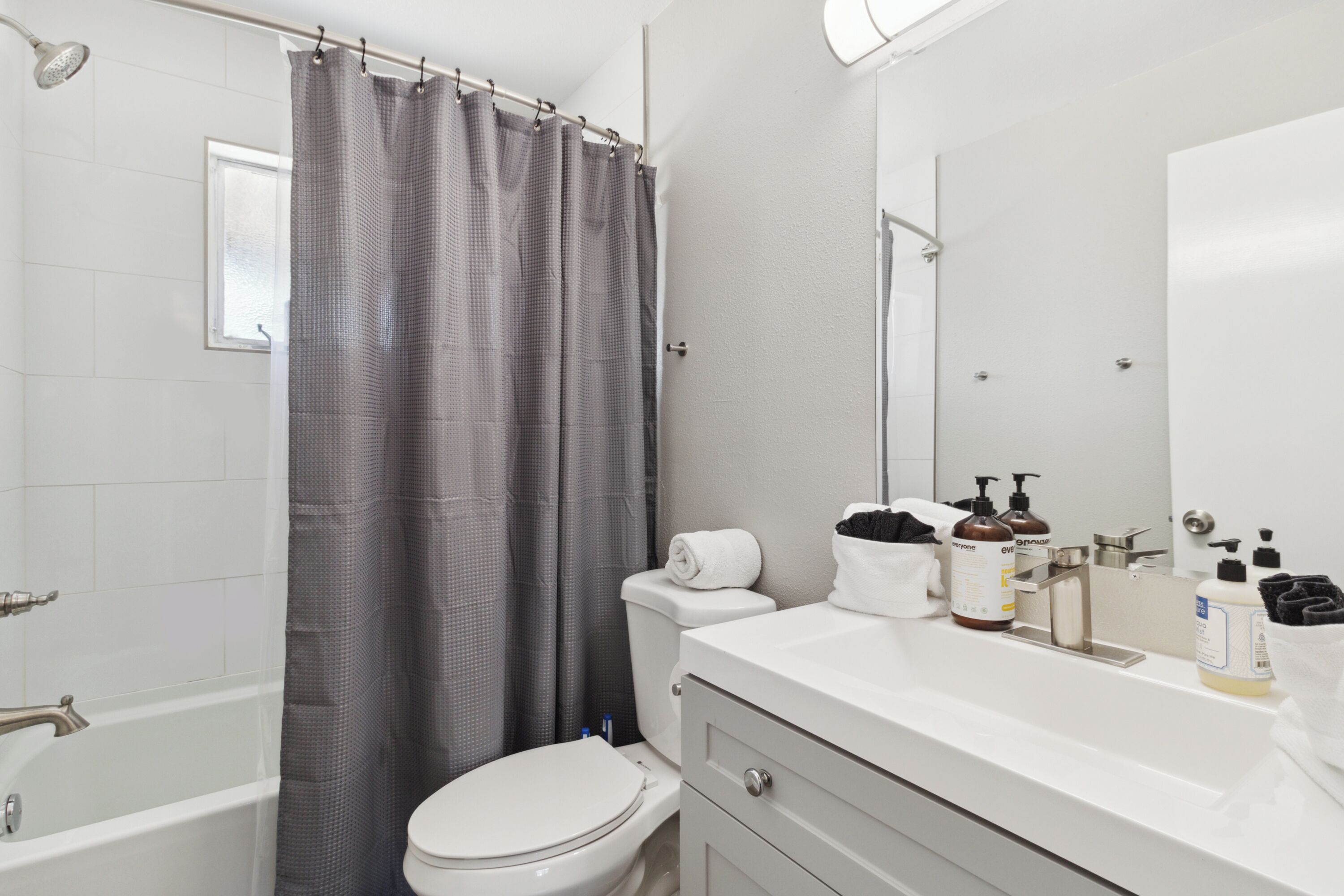 A modern bathroom with a bathtub, toilet, and vanity.