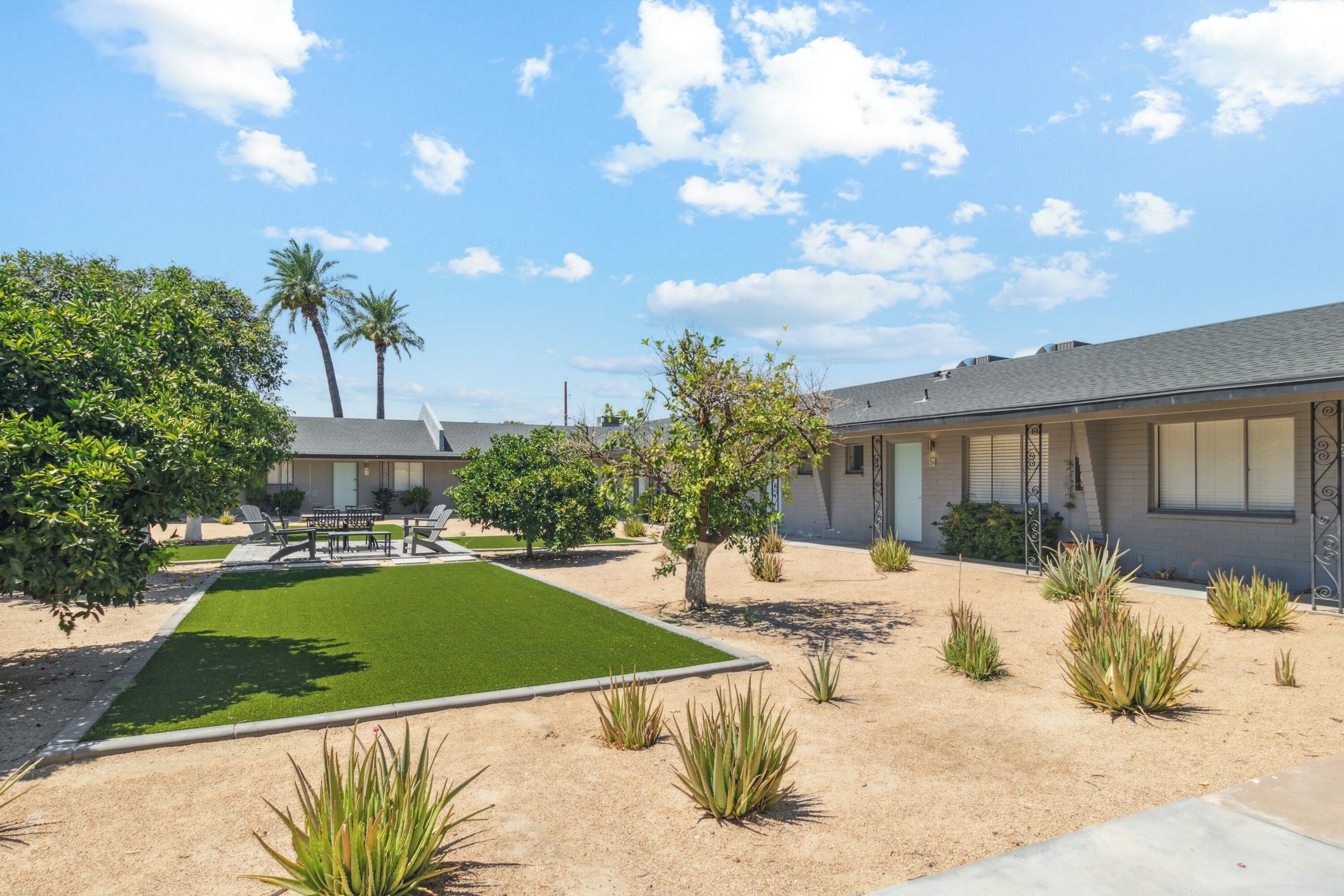 A modern building with a well-maintained lawn, palm trees, and a clear sky.