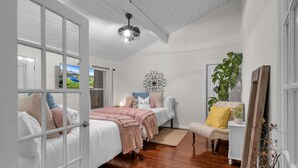 A bedroom with a bed, a chair, a plant, and a decorative wall piece.