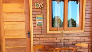 A wooden door with a window above it, a sign with the number 02, and a table with chairs in front. - Pousada Bem Viver (Nobres)