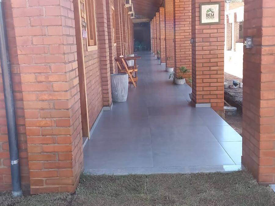 A covered walkway with brick walls and a tiled floor, leading to a building entrance.