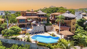 A resort with a swimming pool, multiple buildings with thatched roofs, and lush greenery. - Casa Ceiba Huatulco - Adults Only (Santa María Huatulco)