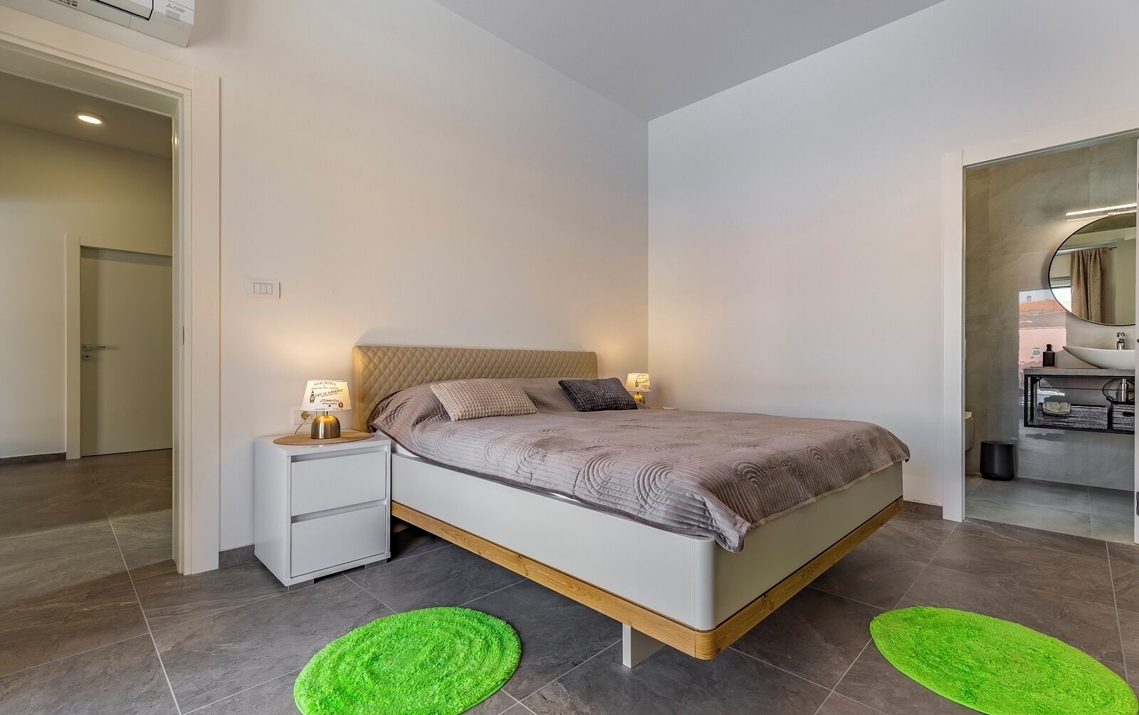 Een moderne slaapkamer met een bed, nachtkastjes en een badkamer die door een open deur zichtbaar is.