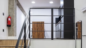 Una escala amb barana negra, un extintor fixat a la paret i un mur revestit de fusta.
