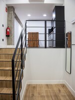 Eine Treppe mit schwarzer Geländer, ein Feuerlöscher an der Wand und eine Wandverkleidung aus Holz.