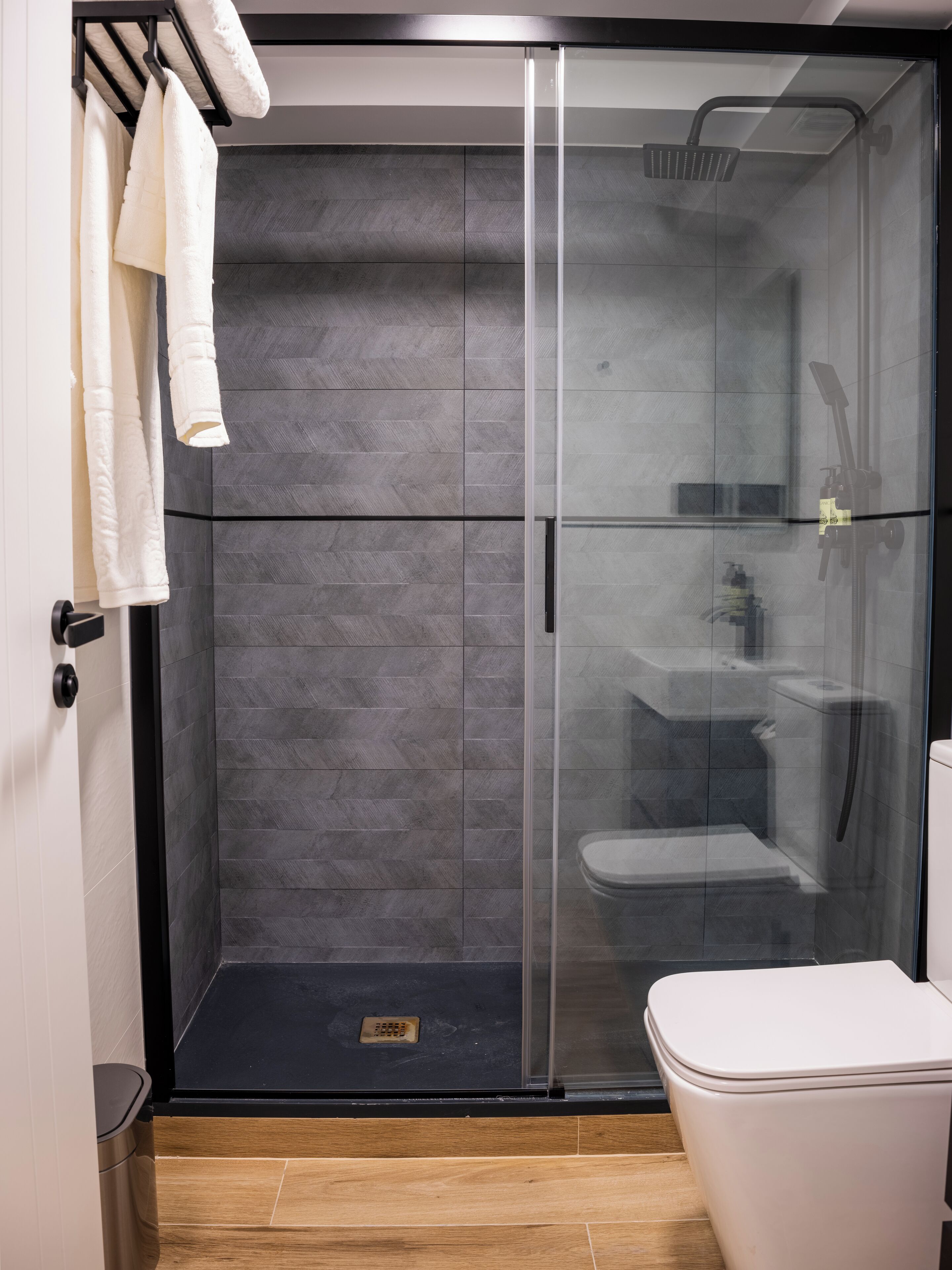 Um banheiro moderno com chuveiro em cabine de vidro, vaso sanitário e porta-toalhas.
