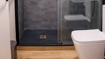 Um banheiro moderno com chuveiro em cabine de vidro, vaso sanitário e porta-toalhas.