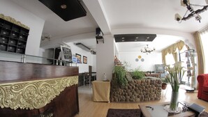 A spacious living area with a wooden reception desk, a stone accent wall, a glass coffee table, and a red armchair. - La Estacion Cusco Hotel (Cusco)