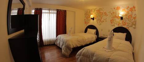 A hotel room with two beds, a TV, a mirror, and a floral wall decoration.