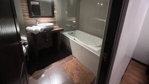 A modern bathroom with a large bathtub, a sink, and a mirror. - La Estacion Cusco Hotel (Cusco)