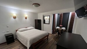 A bedroom with a bed, bedside tables, a wardrobe, a desk with a chair, and a TV mounted on the wall. - La Estacion Cusco Hotel (Cusco)