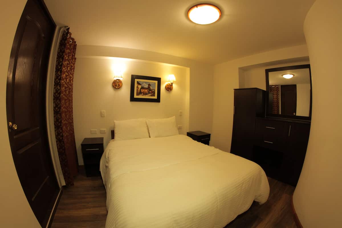 Un dormitorio con una cama grande, una mesita de noche, un tocador y un espejo.