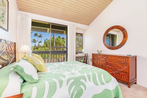 A bedroom with a bed, a wooden dresser, a round mirror, and a balcony with a view of palm trees. - "Da Koa Bar" Paradise at Turtle Bay -Trade Winds, Beaches, Sunshine Rain, Resort (Kahuku)